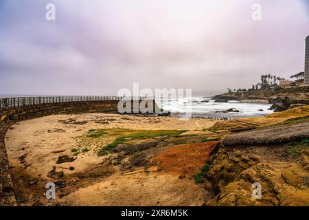 Una vista panoramica di la Jolla Cove con una spiaggia sabbiosa, costa rocciosa e cielo coperto a San Diego, California Foto Stock