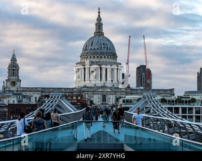 Turisti che camminano sul ponte del millennio in una giornata nuvolosa con la cattedrale di san paolo sullo sfondo Foto Stock