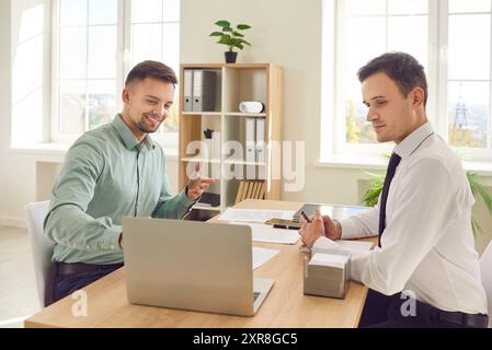 Uomini d'affari felici che lavorano alla scrivania, uomini d'affari occupati al computer portatile Foto Stock