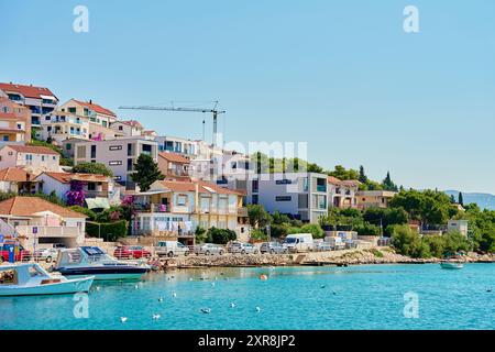 Città di mare con case costiere colorate sulla collina con barche attraccate lungo le acque cristalline. Appartamenti residenziali per vacanze estive ad Adriati Foto Stock