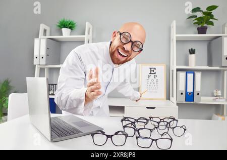 Oftalmologo, divertente medico sorridente che mostra grafico degli occhi, sorride in clinica, aiuta a scegliere Foto Stock