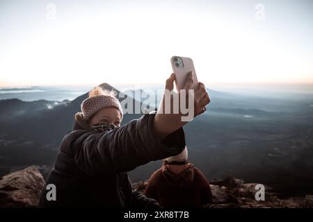 Selfie panoramico all'alba: La donna che viaggia cattura la vista maestosa dell'alba Foto Stock