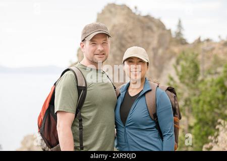 Una coppia di escursionisti sorride alla telecamera con la montagna dietro di loro Foto Stock