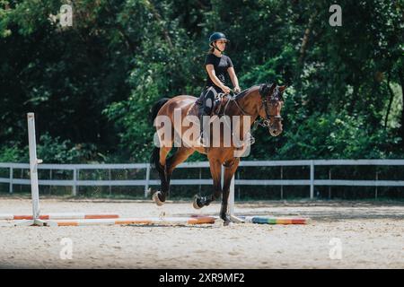 Donna che cavalca un cavallo durante una sessione di allenamento equestre all'aperto in una giornata di sole Foto Stock