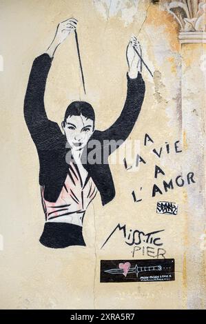 Arles, Francia - 8 marzo 2023: Pittura colorata sulla facciata di una casa, persona in abiti neri Foto Stock