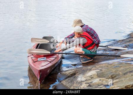 Padre insegna al figlio il kayak in riva al mare con pagaie per kayak in riva al mare, canoa, nautica nel Mar Baltico durante le vacanze estive in famiglia Foto Stock