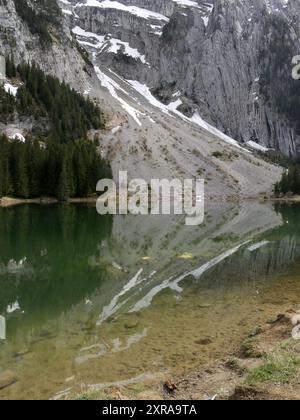 Riflesso della scogliera di montagna con neve nel lac Benit in alta Savoia vicino a Cluses in francia Foto Stock