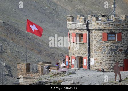 Passo dello Stelvio, Italia - 15 luglio 2023: Passo dello Stelvio in una giornata di sole d'estate, bandiera svizzera di fronte al Rifugio Garibaldi Foto Stock