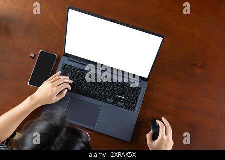 Vista dall'alto del computer portatile con schermi vuoti sul tavolo da ufficio bianco. Il colpo ritagliato di una donna d'affari sta lavorando al computer con isolato Foto Stock