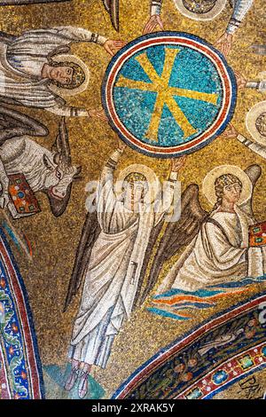 Mosaico religioso che decora il soffitto della basilica cattolica di Ravenna mostrando angeli intorno a un simbolo cristiano Foto Stock