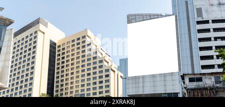 Un grande cartellone bianco è appeso sul lato di un alto edificio in città. Il cartellone è bianco e ha un cielo blu sullo sfondo. L'edificio è m Foto Stock