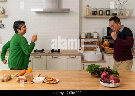 Asiatico senior coppia adulto che cucina cibo sano insieme a casa mentre balla in cucina mattina fine settimana,felicità asiatico vecchio sposare coppia godere ro Foto Stock