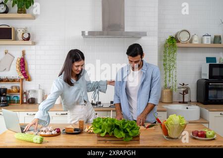 Coppia felice in piedi in cucina a casa, preparando una deliziosa cena, coppie sposate che parlano, si godono una conversazione calda e il processo di coo Foto Stock