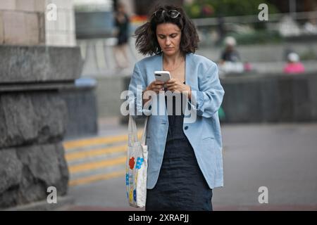 KIEV, UCRAINA - 9 AGOSTO 2024 - Una donna utilizza uno smartphone per strada nel centro di Kiev, capitale dell'Ucraina. Foto Stock