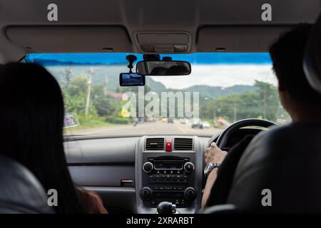 La famiglia e le persone che guideranno due persone sedevano sul sedile anteriore di un'auto che percorreva l'autostrada. Vista posteriore del conducente e del passeggero. Foto Stock