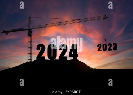 Felice anno nuovo 2024 Concept, silhouette di ingegnere e costruzione per costruire gru di sollevamento 2023 su sfondo viola giallo cielo. Foto Stock