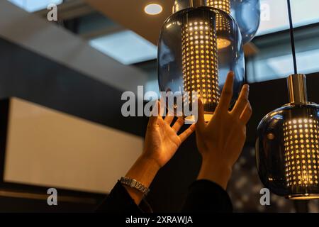 Donna che cambia le lampadine in cucina. Le lampadine elettriche a LED cambiano l'illuminazione domestica. La mano di una donna sta cambiando una lampadina. Cambio manuale di una lampadina Foto Stock