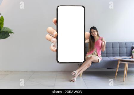 Ad app Bella donna sorridente che tiene in mano lo smartphone con lo schermo bianco del dispositivo vicino alla fotocamera. Gadget con spazio libero vuoto per il mockup, ba Foto Stock