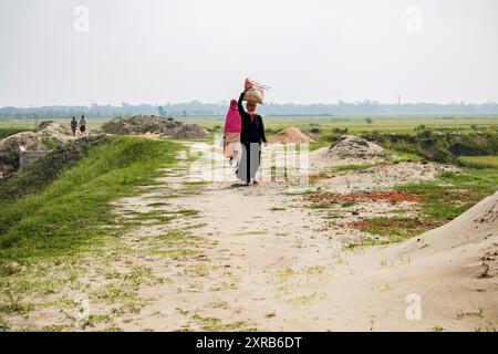 Contadino bengalese con mucche sulla strada vanno a depositare. La vita rurale quotidiana dei contadini. Bangladesh - 22 aprile 2024 Foto Stock