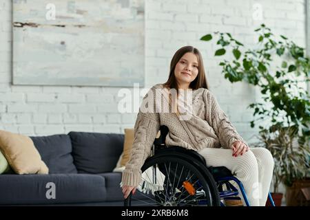 Una giovane donna in sedia a rotelle siede in un soggiorno, guardando con calma la macchina fotografica. Foto Stock