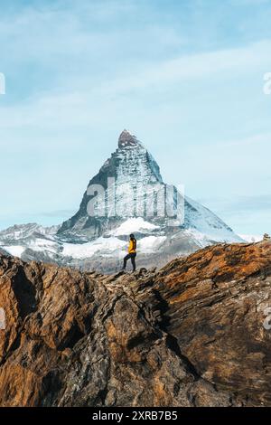 Una donna in piedi sulla cima di una montagna rocciosa con l'iconico Monte Cervino nella giornata di sole a Zermatt, Svizzera Foto Stock