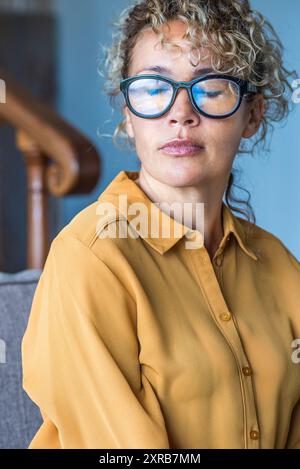 Occhi chiusi ritratto triste espressione giovane adulta seduta sola sul divano - depressione malattia e solitudine per caucasico donne - porto Foto Stock