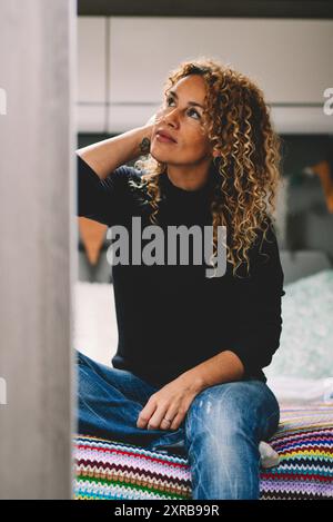 Una bella signora si siede in camera da letto sul camper interno. Concetto di viaggiatore femminile e stile di vita nomade alternativo. Signora che si gode il relax e la vacanza all'interno di un camper Foto Stock