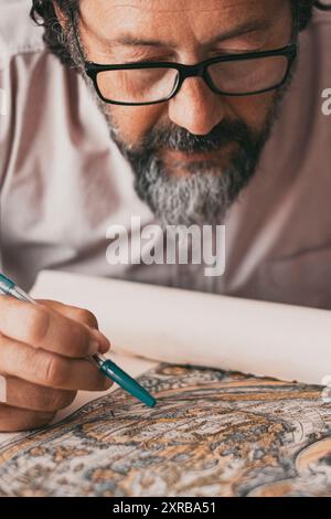 Ritratto ravvicinato di un uomo impegnato a studiare una mappa di disegno su carta sul tavolo della scrivania. Attività professionale dei lavoratori. Persone mature che lavorano concentrate. Indossare occhiali. Attività di svago al coperto Foto Stock