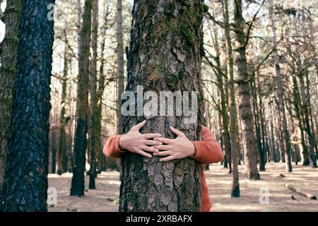 Amante della natura che abbraccia il tronco con muschio verde nella foresta tropicale. Sfondo verde naturale. Il concetto di persone ama la natura e protegge dalla deforestazione, dall'inquinamento o dal cambiamento climatico Foto Stock