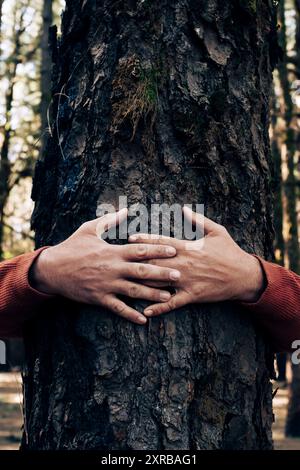 Amante della natura che abbraccia il tronco con muschio verde nella foresta tropicale. Sfondo verde naturale. Il concetto di persone ama la natura e protegge dalla deforestazione, dall'inquinamento o dal cambiamento climatico Foto Stock