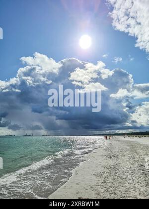 I vacanzieri in lontananza godono dell'atmosfera serale con l'ultima luce del sole sul bordo dell'acqua nella località balneare Baltica di Prerow, in Germania Foto Stock