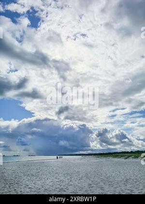 I vacanzieri lontani camminano sulla spiaggia e sperimentano l'atmosfera serale con il suggestivo cielo nuvoloso dopo il tramonto sul bordo dell'acqua nel Balt Foto Stock