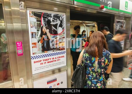 Asia, Singapore, MRT, passeggeri in Subway Carriage e poster di sensibilizzazione al crimine Foto Stock