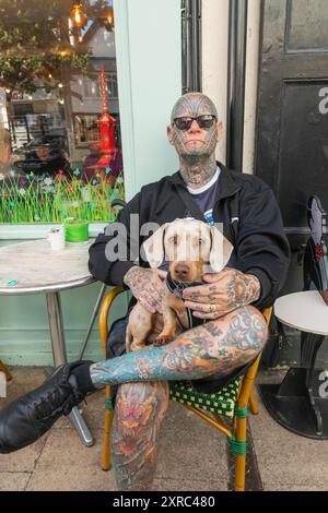 Inghilterra, Kent, Faversham, uomo tatuato seduto con cane in giro Foto Stock