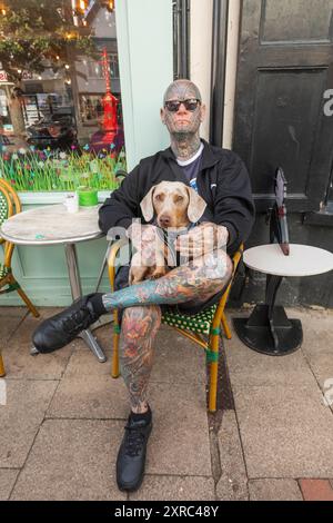 Inghilterra, Kent, Faversham, uomo tatuato seduto con cane in giro Foto Stock