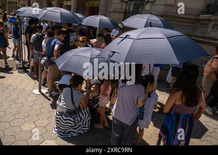 Barcellona, Spagna. 09 agosto 2024. Un gruppo di turisti protetti da ombrelloni è visto in coda per visitare la modernista Casa Batlló. Barcellona soffre ancora una volta di un'ondata di caldo con temperature che raggiungono i 40 gradi Celsius sull'asfalto del centro città. Credito: SOPA Images Limited/Alamy Live News Foto Stock