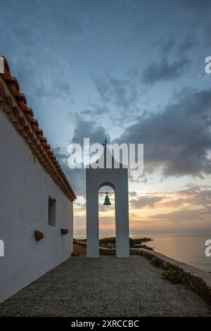 Piccola chiesa bianca in tipico stile architettonico greco, situata su una roccia lavica, circondata dal Mar Mediterraneo, Cappella di Agios Nikolaos all'alba, Zante, Isole Ionie, Grecia Foto Stock