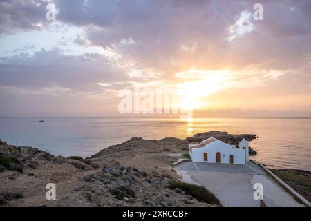 Piccola chiesa bianca in tipico stile architettonico greco, situata su una roccia lavica, circondata dal Mar Mediterraneo, Cappella di Agios Nikolaos all'alba, Zante, Isole Ionie, Grecia Foto Stock