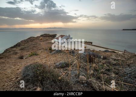 Piccola chiesa bianca in tipico stile architettonico greco, situata su una roccia lavica, circondata dal Mar Mediterraneo, Cappella di Agios Nikolaos all'alba, Zante, Isole Ionie, Grecia Foto Stock