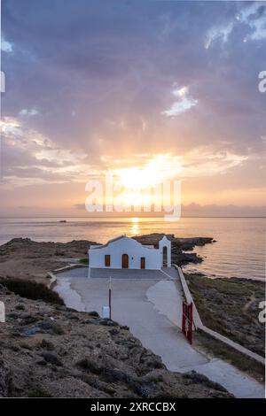 Piccola chiesa bianca in tipico stile architettonico greco, situata su una roccia lavica, circondata dal Mar Mediterraneo, Cappella di Agios Nikolaos all'alba, Zante, Isole Ionie, Grecia Foto Stock