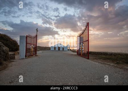 Piccola chiesa bianca in tipico stile architettonico greco, situata su una roccia lavica, circondata dal Mar Mediterraneo, Cappella di Agios Nikolaos all'alba, Zante, Isole Ionie, Grecia Foto Stock