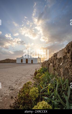 Piccola chiesa bianca in tipico stile architettonico greco, situata su una roccia lavica, circondata dal Mar Mediterraneo, Cappella di Agios Nikolaos all'alba, Zante, Isole Ionie, Grecia Foto Stock