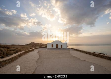 Piccola chiesa bianca in tipico stile architettonico greco, situata su una roccia lavica, circondata dal Mar Mediterraneo, Cappella di Agios Nikolaos all'alba, Zante, Isole Ionie, Grecia Foto Stock