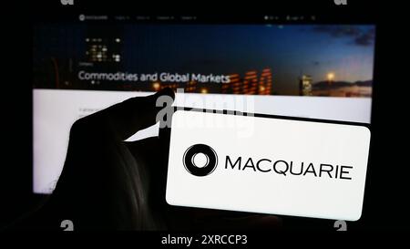 Persona che detiene un telefono cellulare con il logo della società finanziaria australiana Macquarie Group Limited davanti alla pagina Web. Mettere a fuoco il display del telefono. Foto Stock