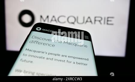 Smartphone con sito web della società finanziaria australiana Macquarie Group Limited davanti al logo aziendale. Mettere a fuoco in alto a sinistra sul display del telefono. Foto Stock