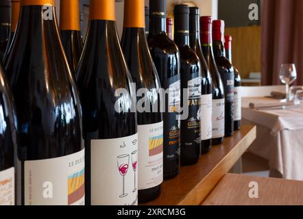 MORUZZO, Italia - 7 luglio 2024: Fila di bottiglie di vino italiano su un tavolo di legno in un elegante ristorante Foto Stock