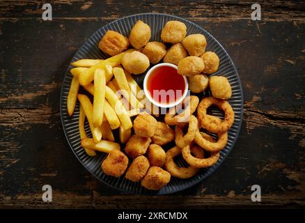 piatto di vari spuntini fritti sul vecchio tavolo in legno, vista dall'alto Foto Stock