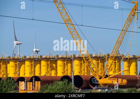 Umschlagplatz für Offshore Windanlagen, Die vom Hersteller hier her transportiert werden, um dann mit Spezialschiffen zu den Baustellen der Windparks in der Nordsee verschifft werden, hier, gelb, s.g. Transition Pieces Giacche, Die auf den, im Meeresboden gerammten Monopile Fundamenten montiert werden, darauf wird dann das draeigliche, Windand, Windantiert, Windantliche, Windann draeigliche, Windanlagen im Hafengebiet von Vlissingen-Oost, Niederlande, Offshore Windpark Logistik *** punto di trasbordo per turbine eoliche offshore, trasportate qui dal fabbricante e poi spedite con navi speciali ai cantieri eolici Foto Stock