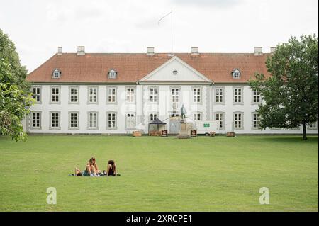 Castello di Odense in un parco e tre ragazze sedute nell'erba, una brillante giornata estiva, Odense, Danimarca, 3 agosto 2024 Foto Stock