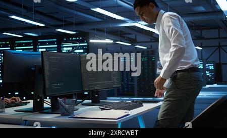 Informatico del data center responsabile dell'installazione di apparecchiature di rete per la risoluzione delle attività. Uomo indiano al lavoro che fa manutenzione sull'infrastruttura della sala server, telecamera B. Foto Stock